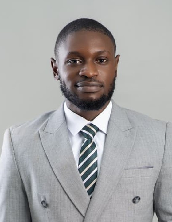 Portrait of Paul Nwani, Director of Green Cycler, in a grey double-breasted suit and a green striped tie